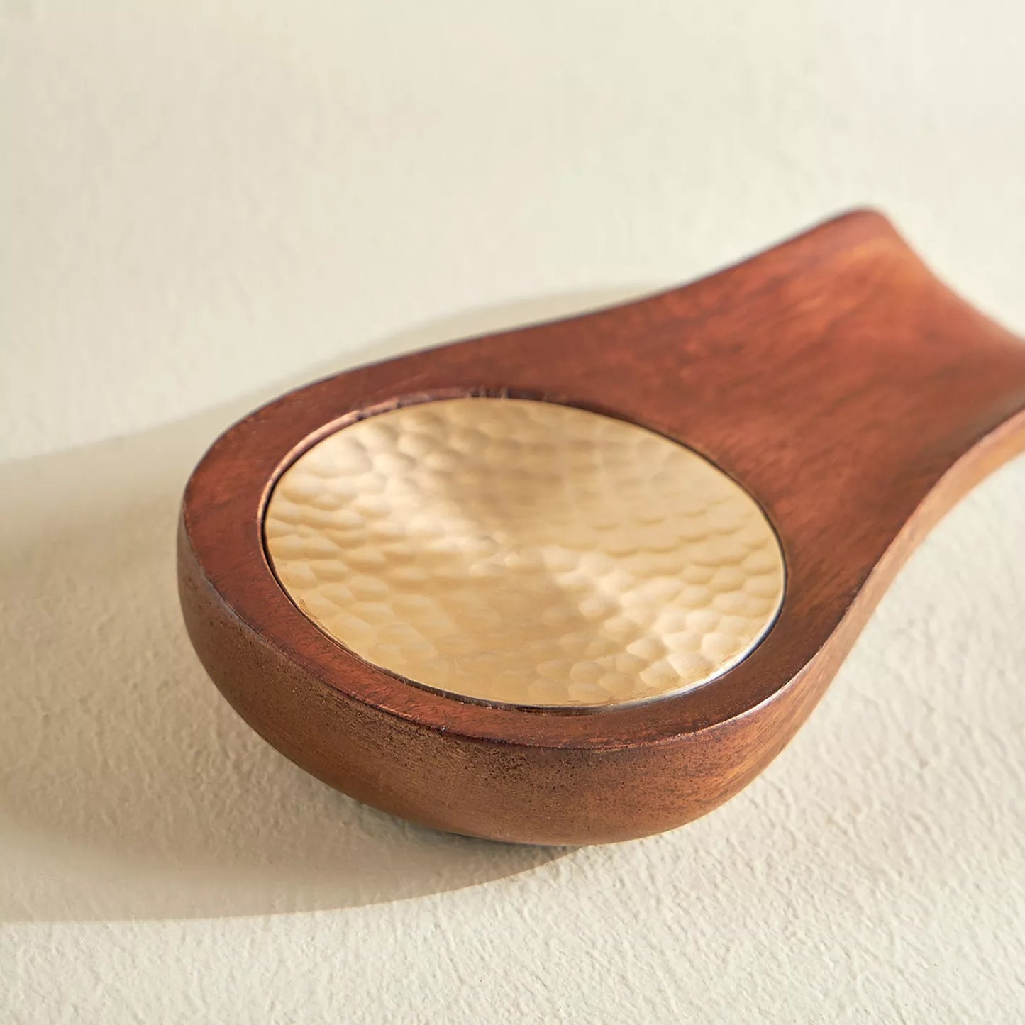 Wooden spoon with a aluminum bowl on a beige background