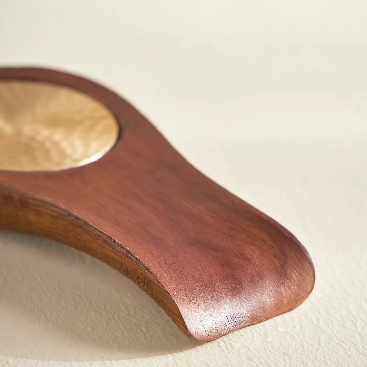 Wooden paddle with a metallic center on a beige background
