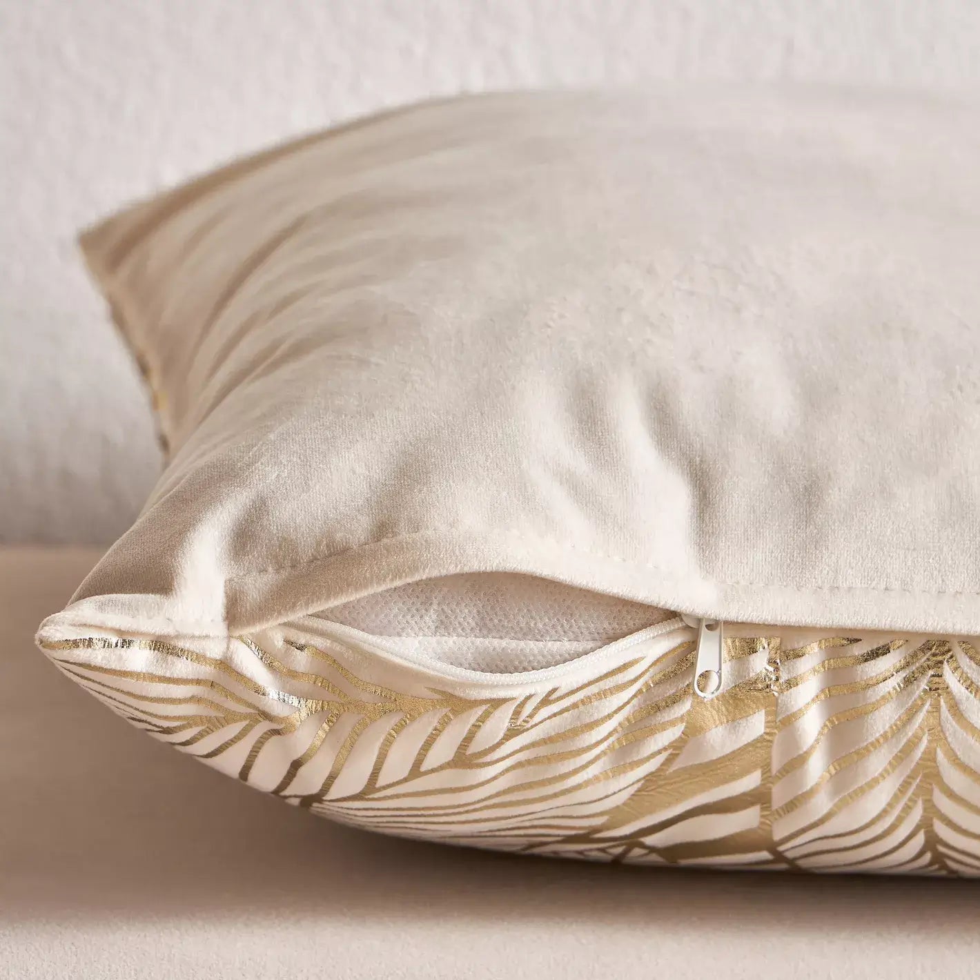Decorative pillow with gold leaf pattern on a neutral background