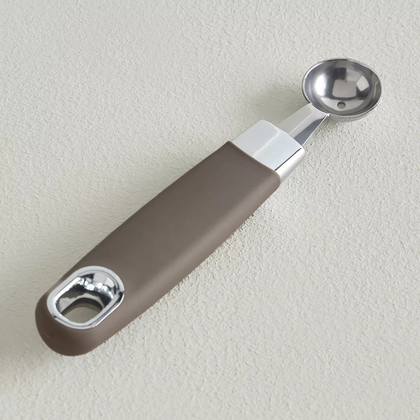 Measuring spoon with brown handle and silver end on a light gray background