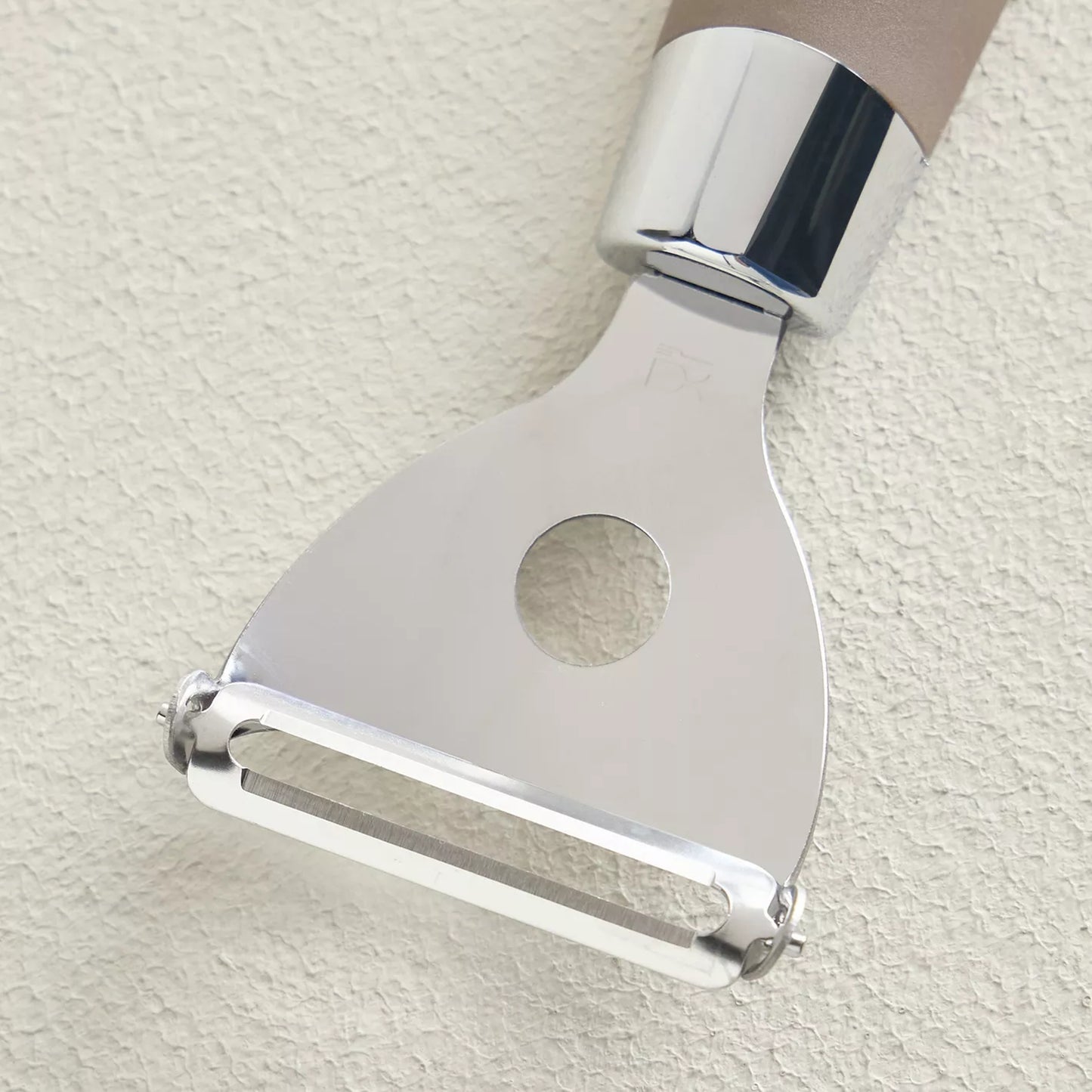 Metallic peeler on a light beige background