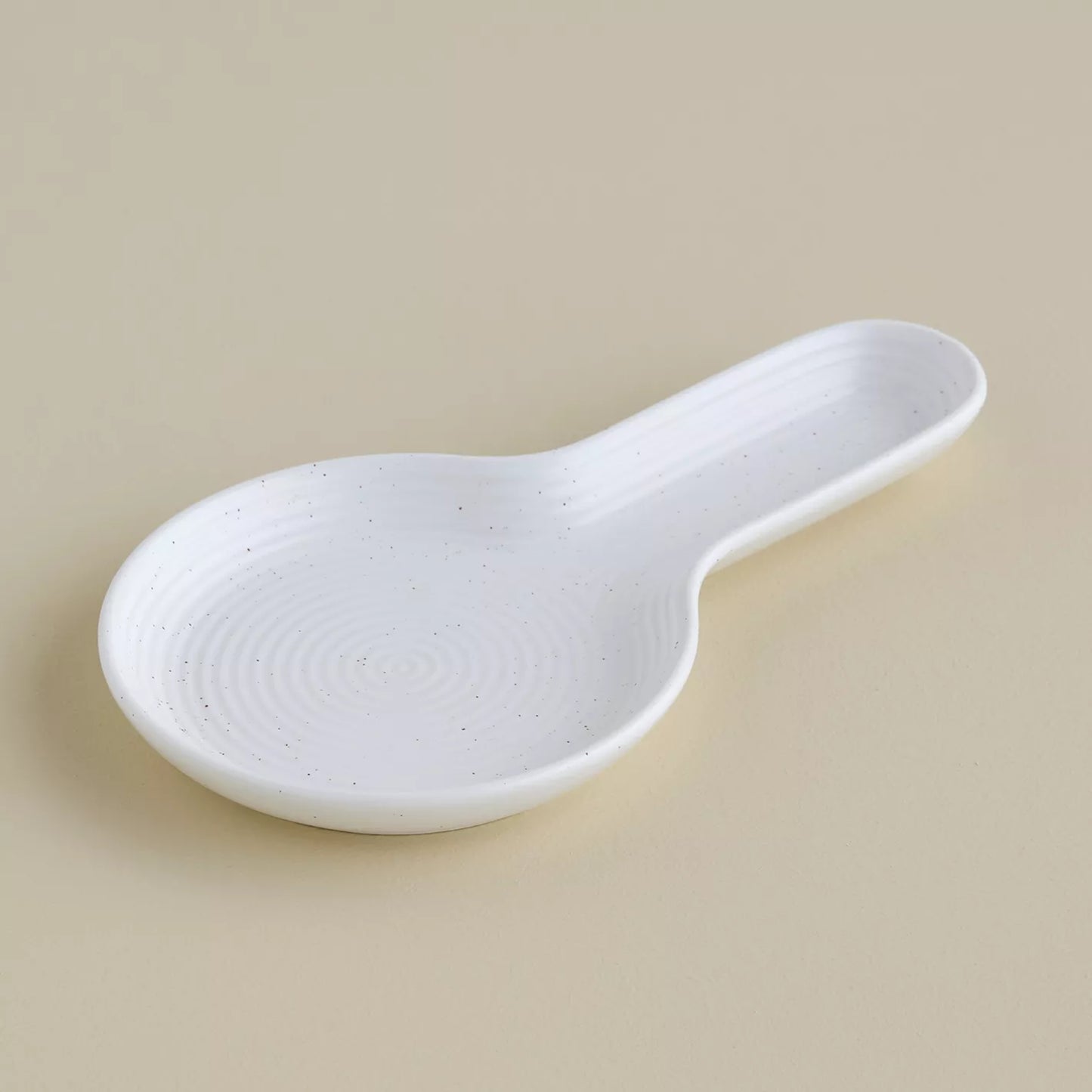 White ceramic spoon rest on a beige background