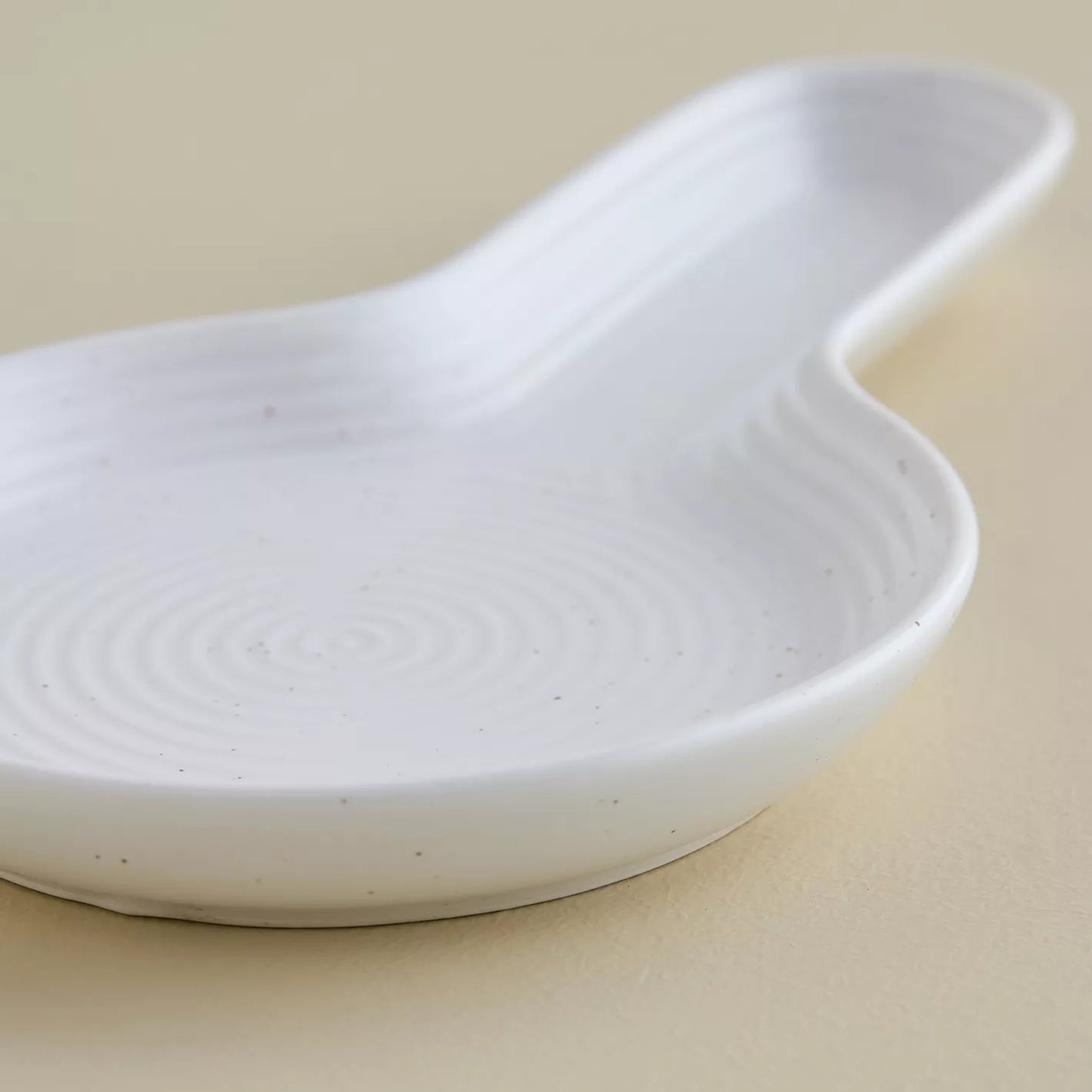 White ceramic dish with wavy edge on a beige background