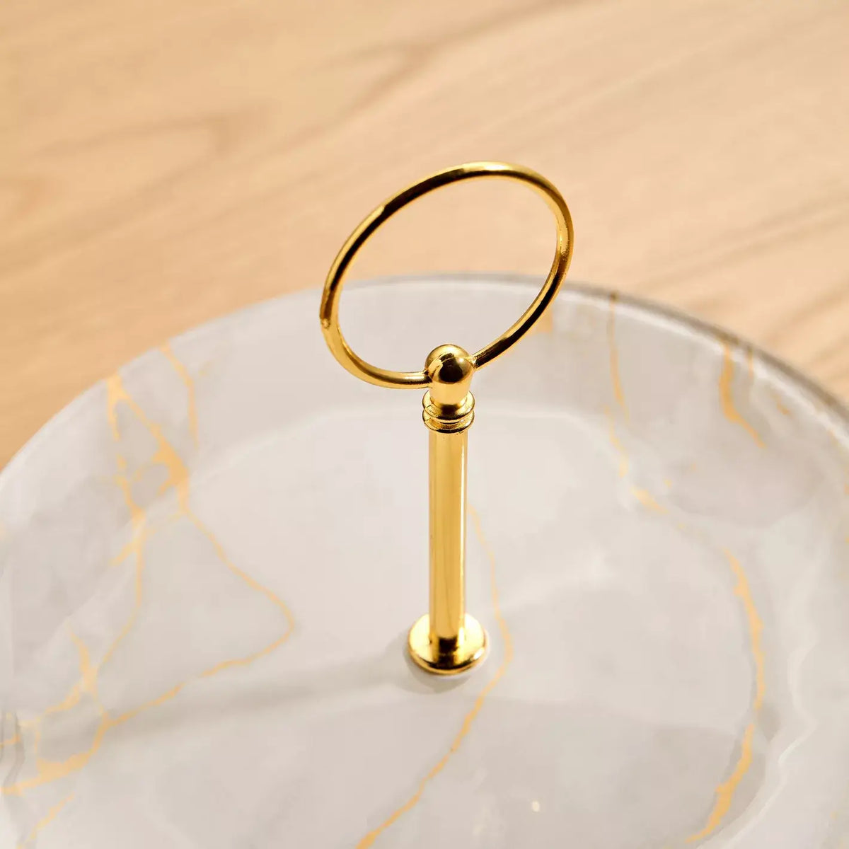 Gold ring stand on a marble surface with a beige background