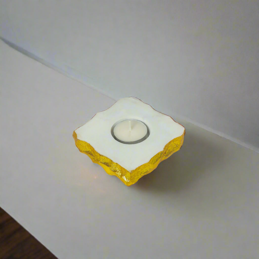 Decorative candle holder with yellow base and white top on a neutral surface