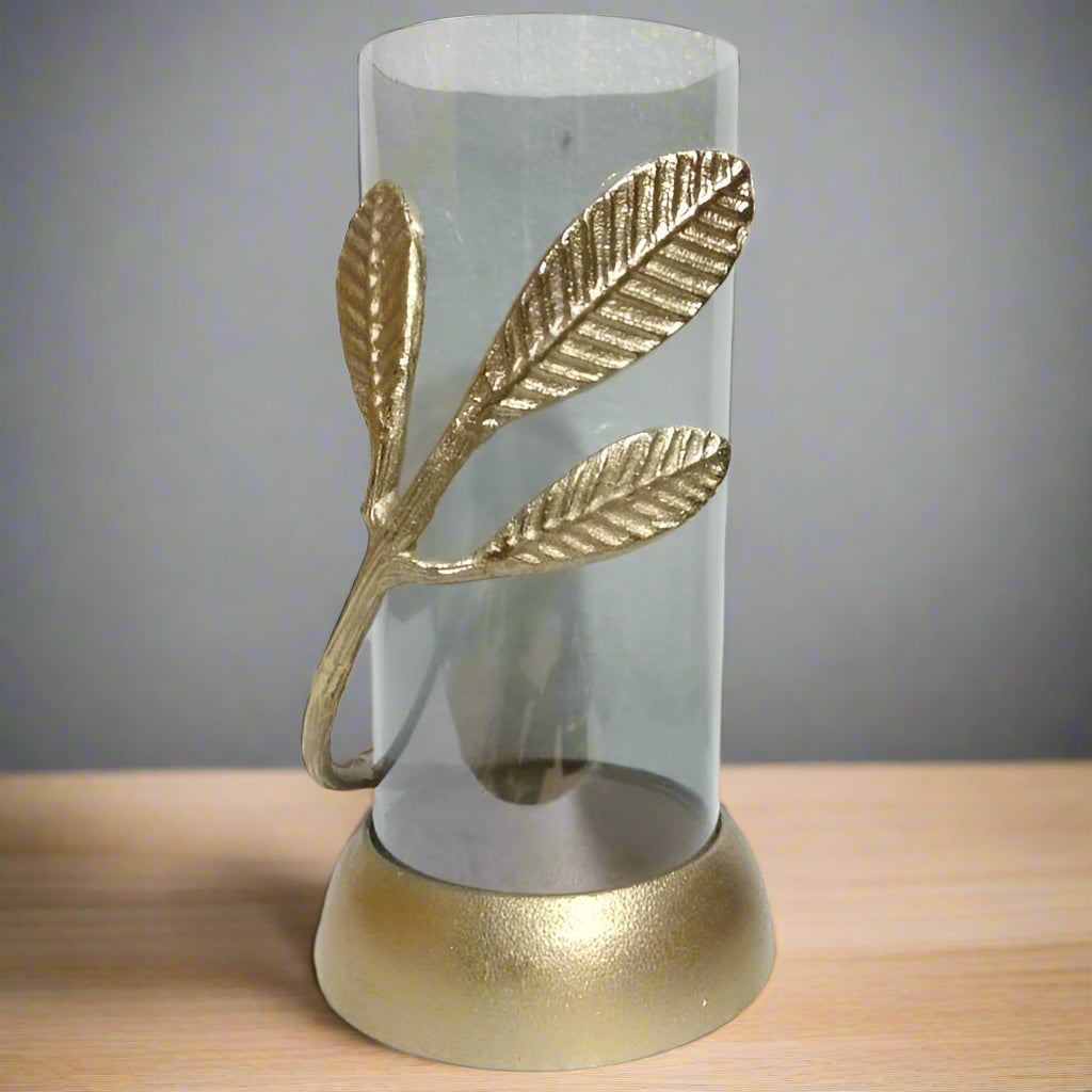 A decorative leaf candle holder with a clear glass cylinder and a golden metal framework shaped like ginkgo biloba leaves, with a base matching the golden finish.