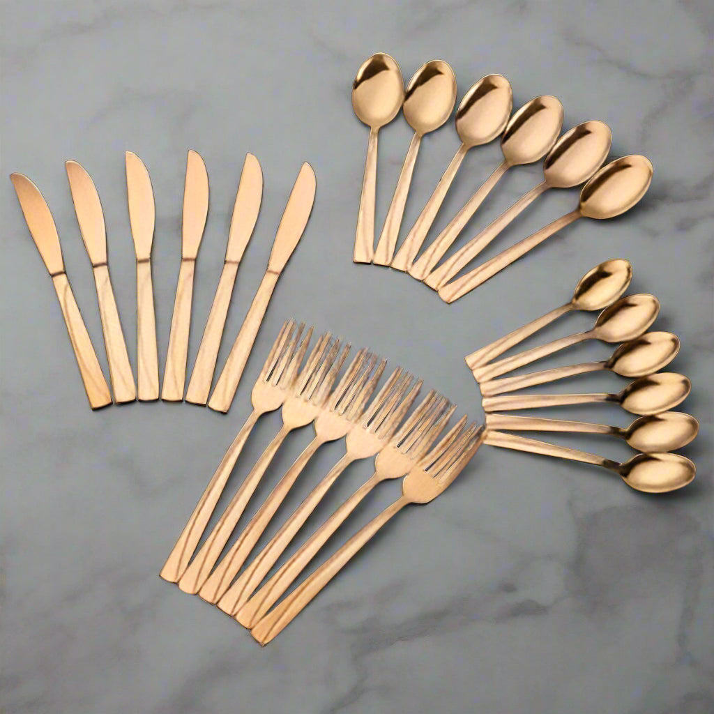Set of gold-colored cutlery including knives, forks, and spoons on a black background