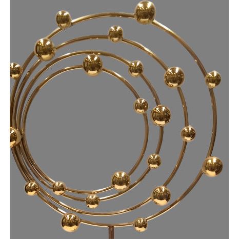 Decorative gold metal sculpture with spherical elements on a gray background