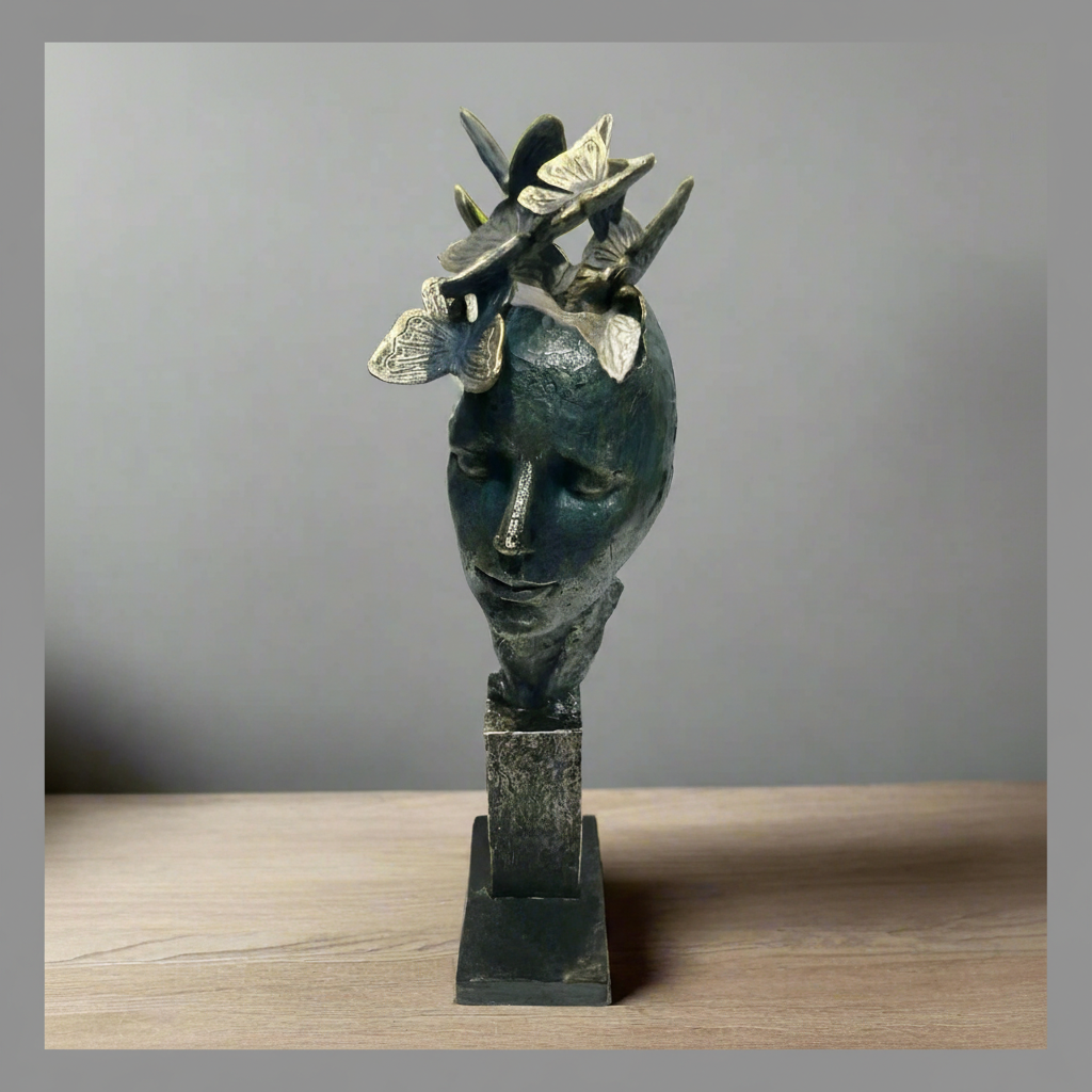 Bronze sculpture of a face with butterflies on a gray background