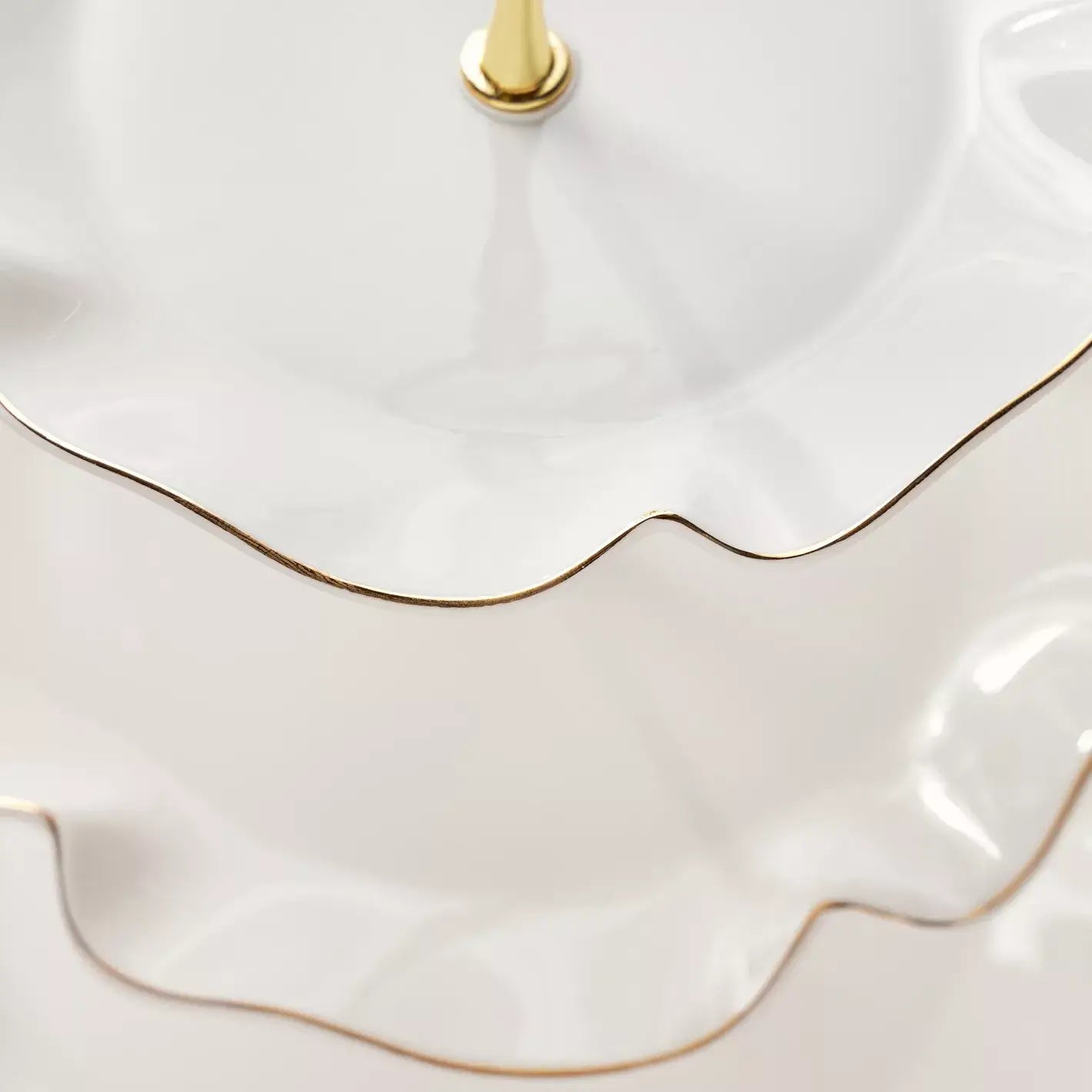 Close-up of a white ceramic cake stand with gold trim