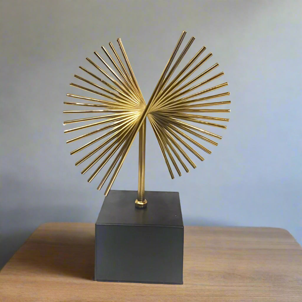 Decorative gold sculpture on a black base against a white background