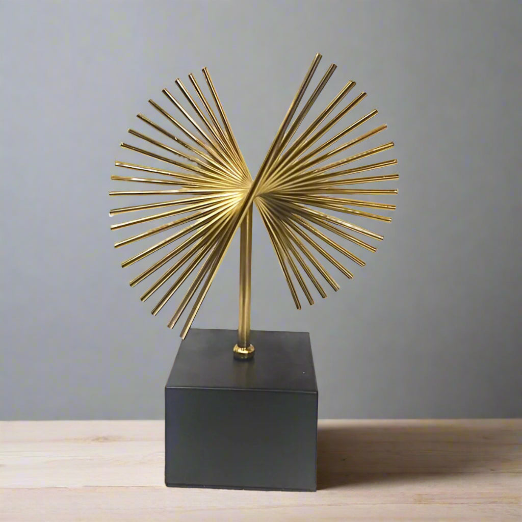 Decorative gold sculpture on a black base against a white background