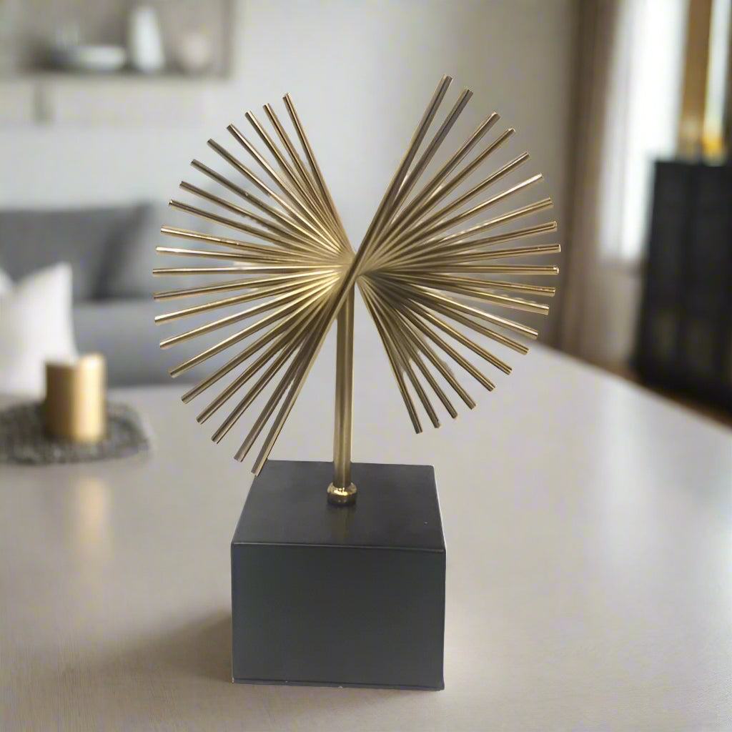 A gold metal palm tree sculpture on a black base, with a white background.
