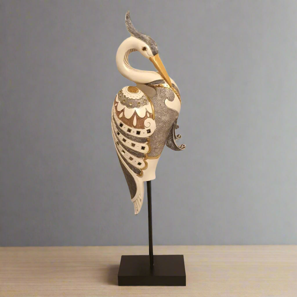 Decorative heron sculpture on a stand against a gray background