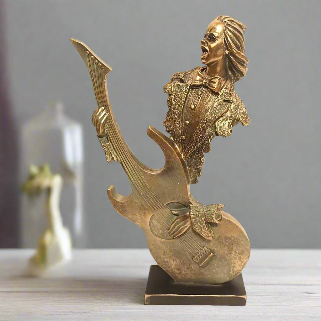 Gold figurine of a musician with a guitar on a gray background