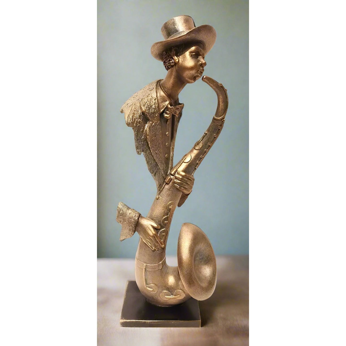 Bronze statue of a person playing a saxophone against a light blue background