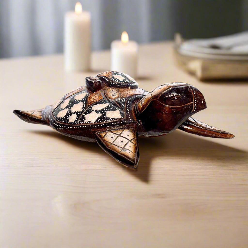 Decorative turtle figurine on a wooden surface with candles in the background