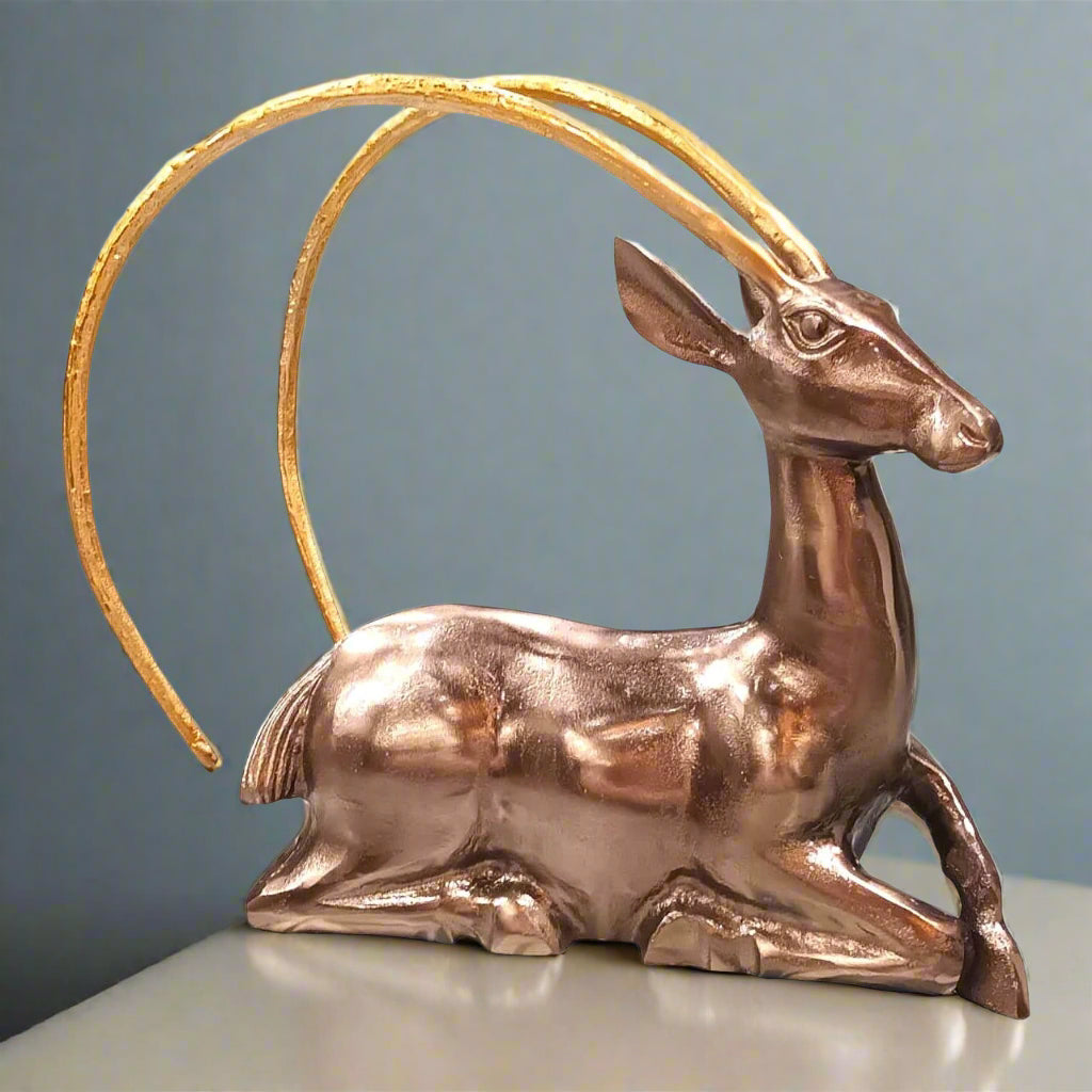 Bronze gazelle figurine with gold horns on a gray background