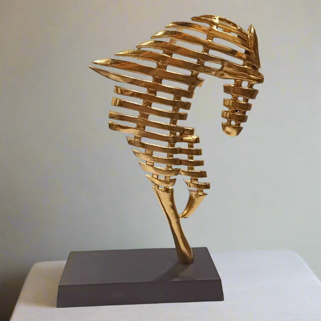 Gold seahorse sculpture on a black base against a white background