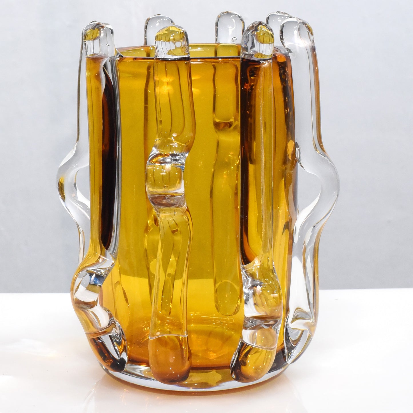 Glass pitcher filled with a yellow liquid on a white background