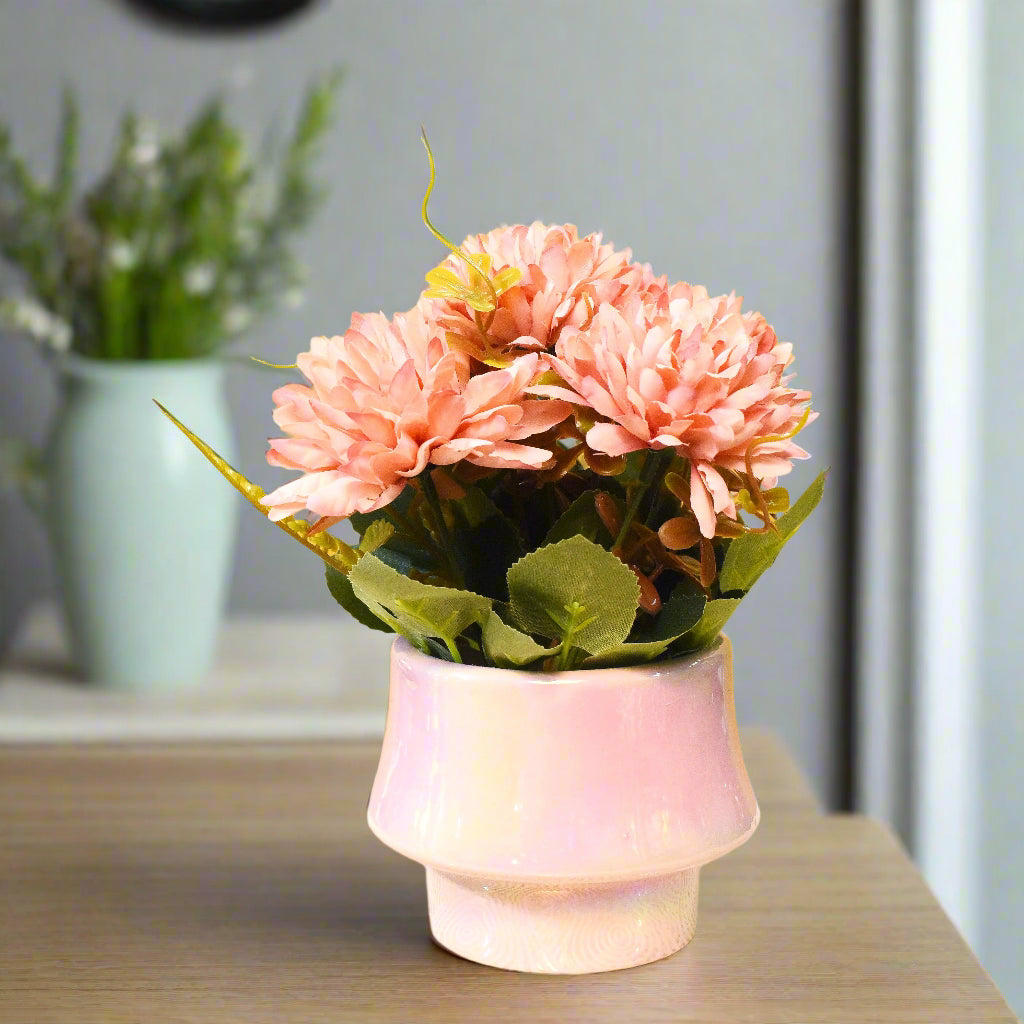 Pink artificial flowers in a pink vase on a yellow background