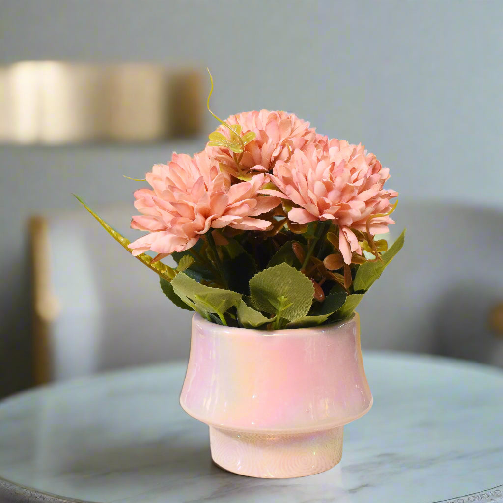 Pink artificial flowers in a ceramic pot on a textured surface with a yellow background