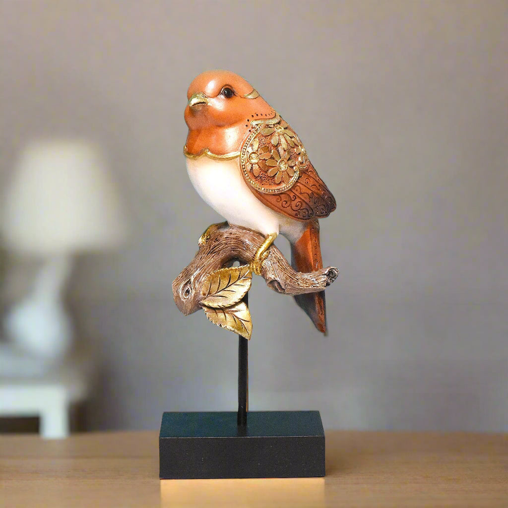 Decorative bird figurine with gold accents on a stand against a neutral background