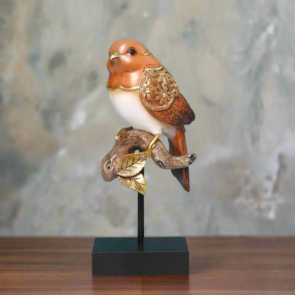 Decorative bird figurine with gold accents on a stand against a teal wall.