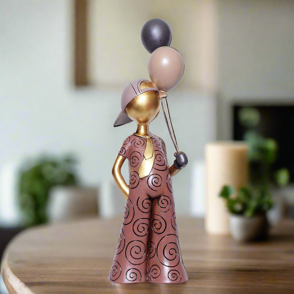 Decorative figurine of a person with balloons on a table in a blurred indoor setting