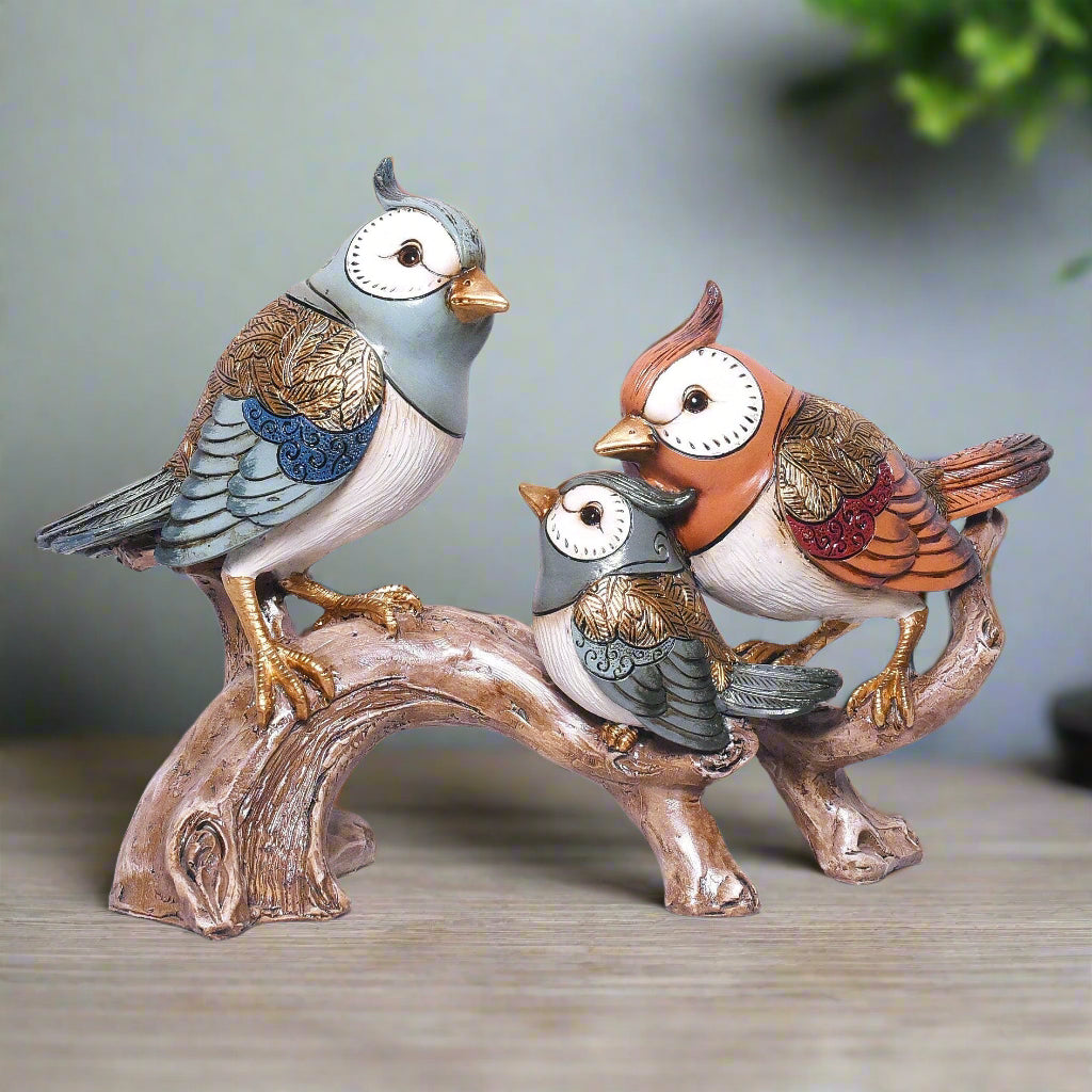Three colorful bird figurines on a branch against a white background