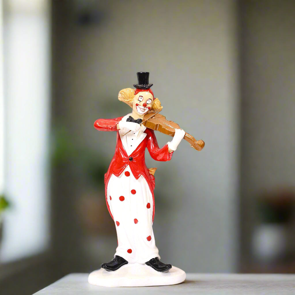 Clown figurine in a red and white outfit with black polka dots, holding a violin, on a blurred background.