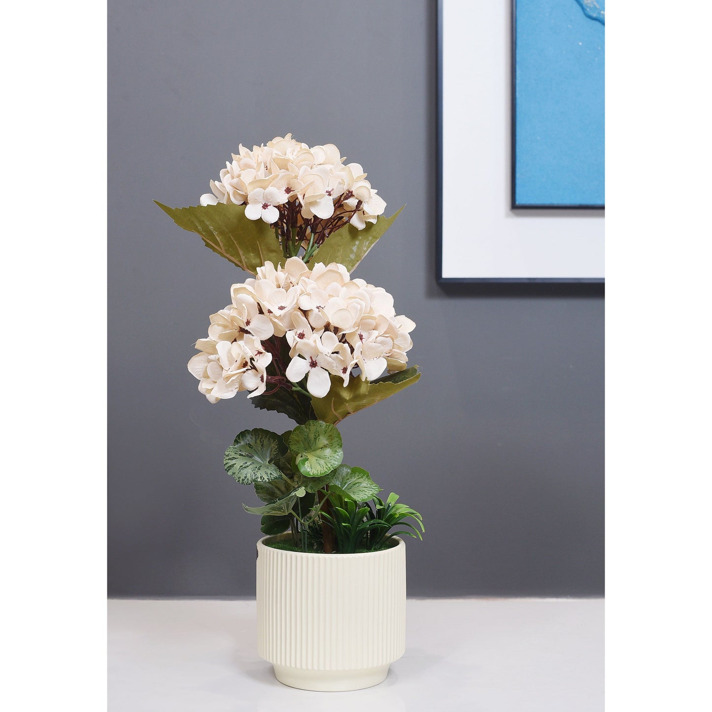 Artificial potted plant with white flowers and green leaves on a gray surface.