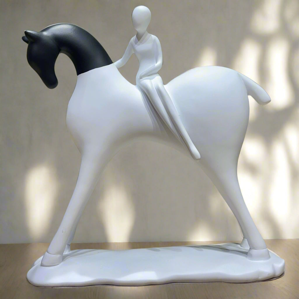 White sculpture of a person riding a horse on a wooden surface with a green background