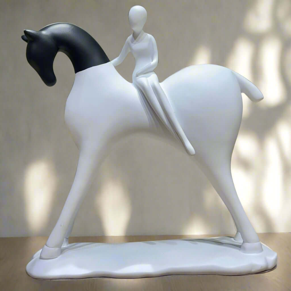 White sculpture of a person riding a horse on a wooden surface with a green background