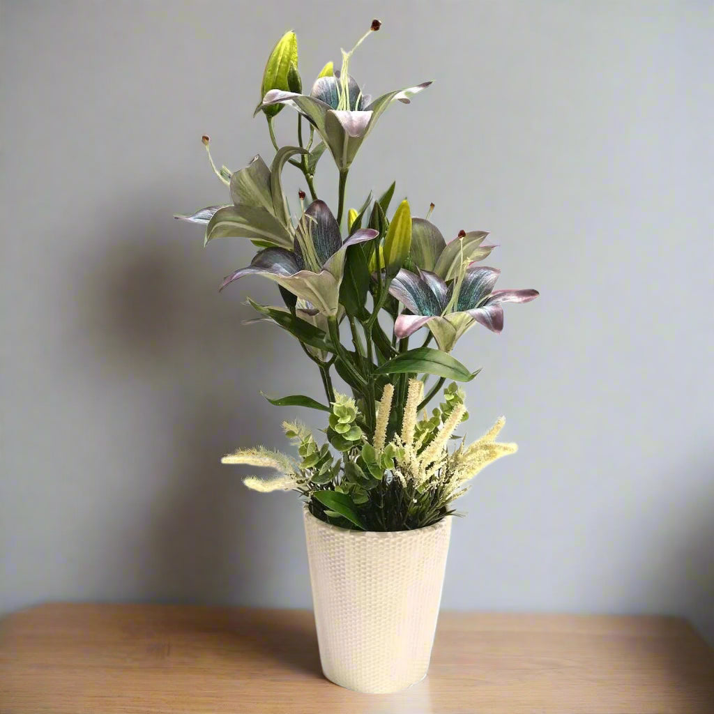 Artificial plant in a pot with green leaves and purple flowers on a white background