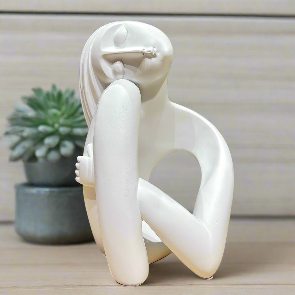 White abstract sculpture on a wooden surface with a green background