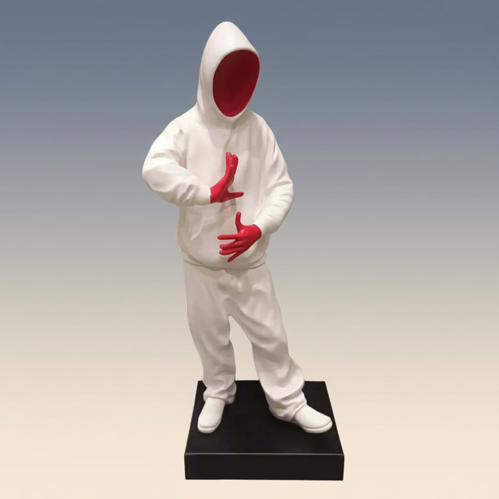 Statue of a figure in a white outfit with red gloves on a wooden surface and gray background
