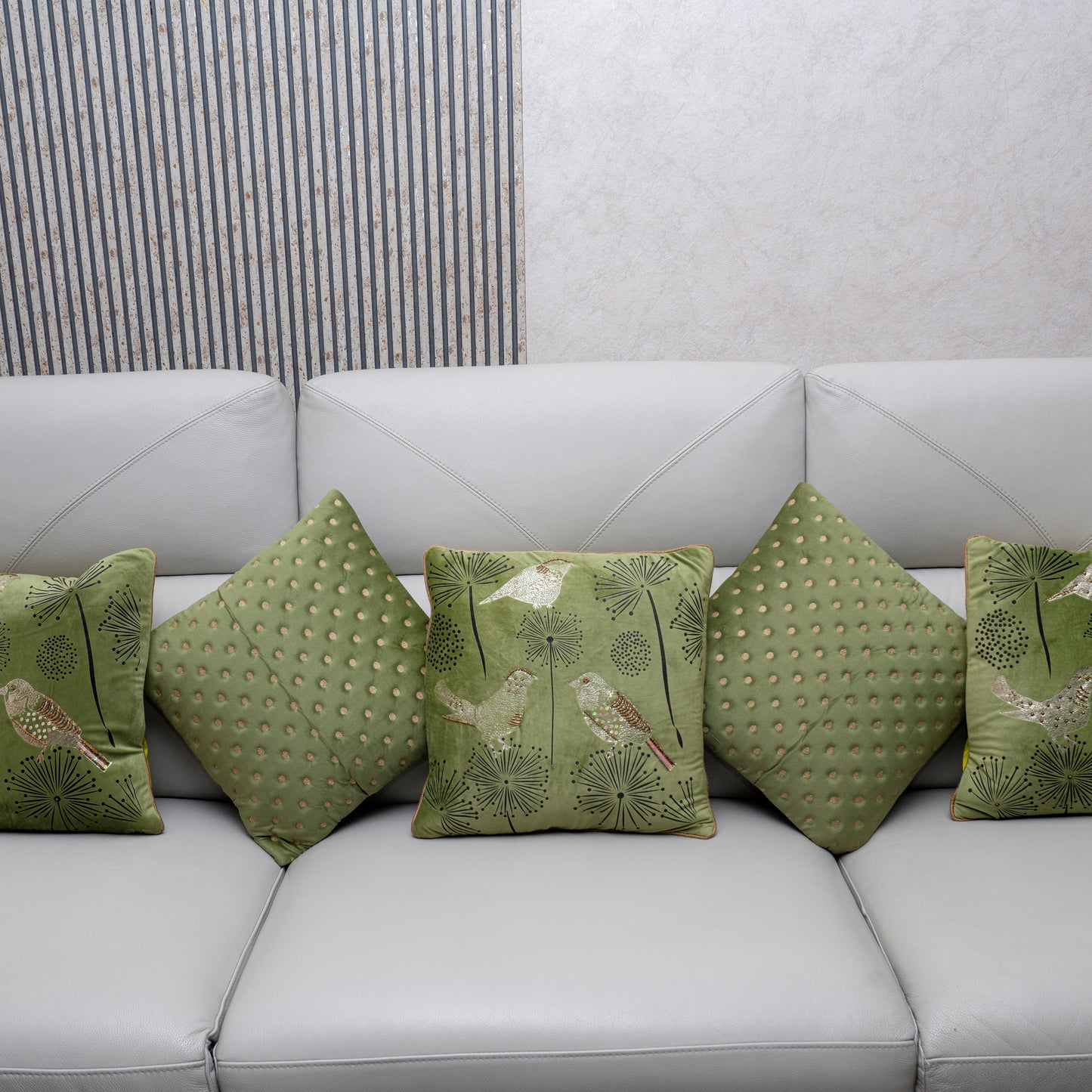 Green patterned cushions on a white sofa against a neutral wall.