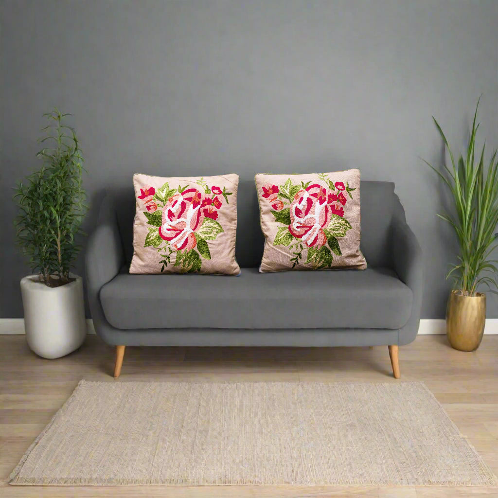 Two floral-patterned cushions on a green couch against a plain background