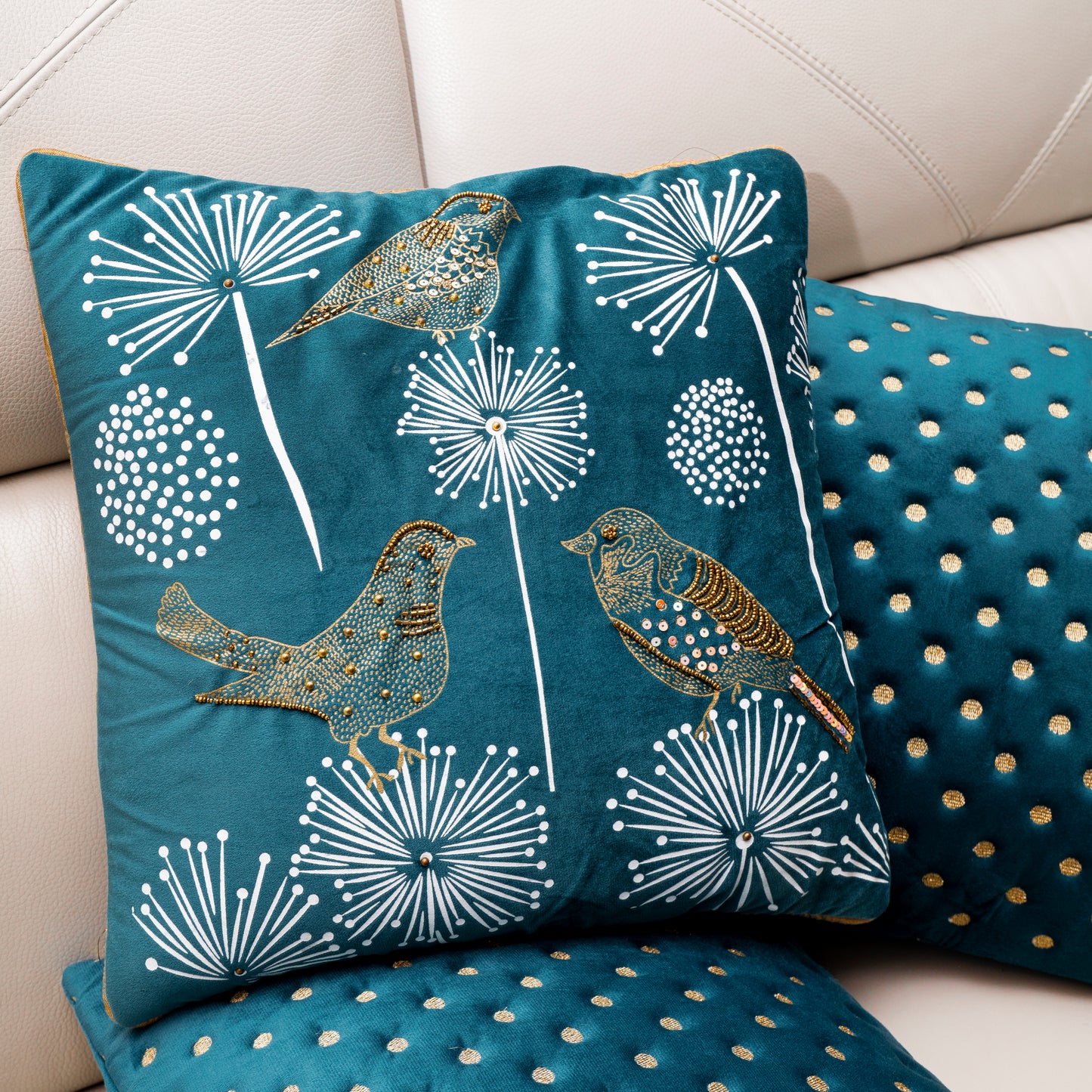 Decorative pillows with bird and dandelion design on a white sofa.