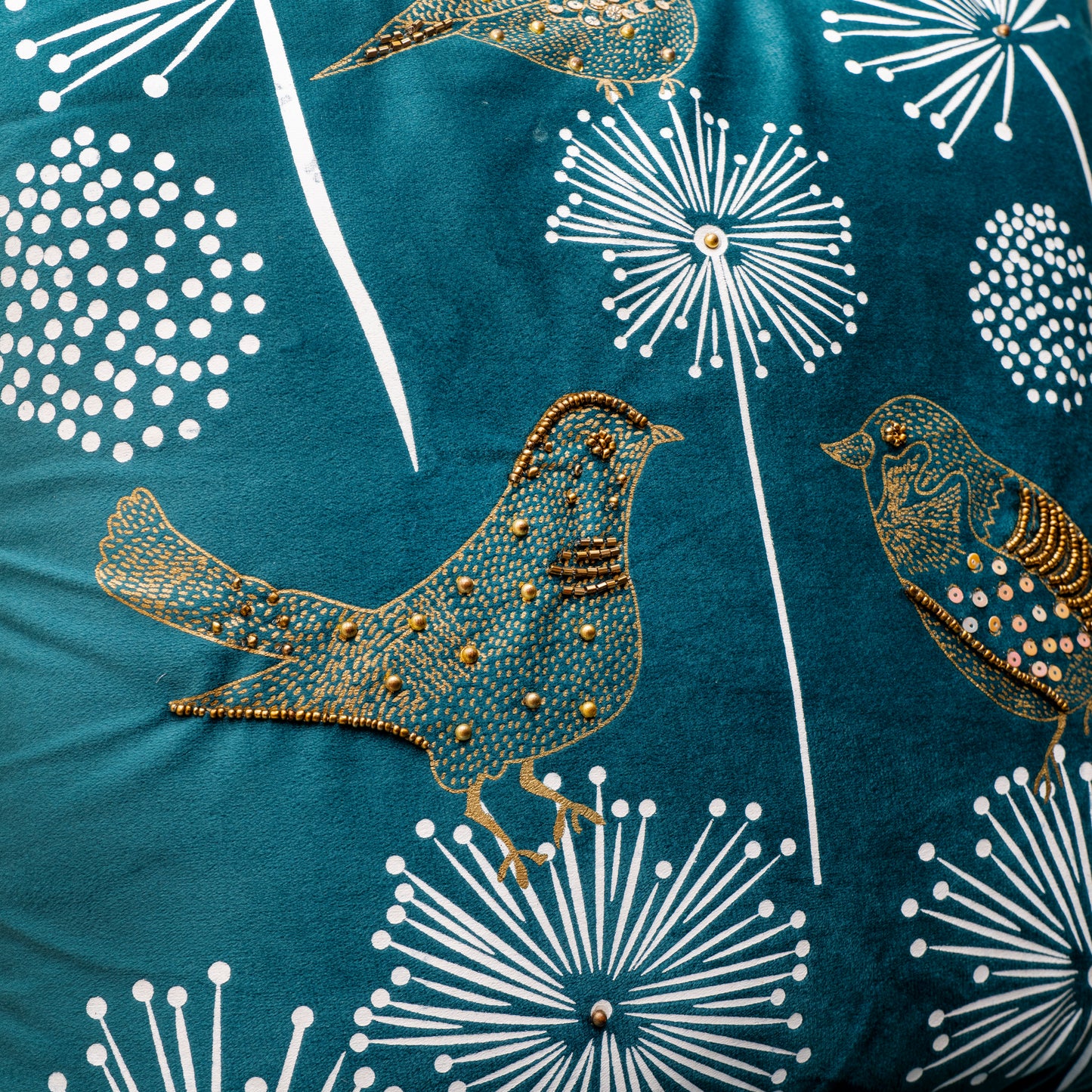 Embroidered birds and floral patterns on a blue fabric background