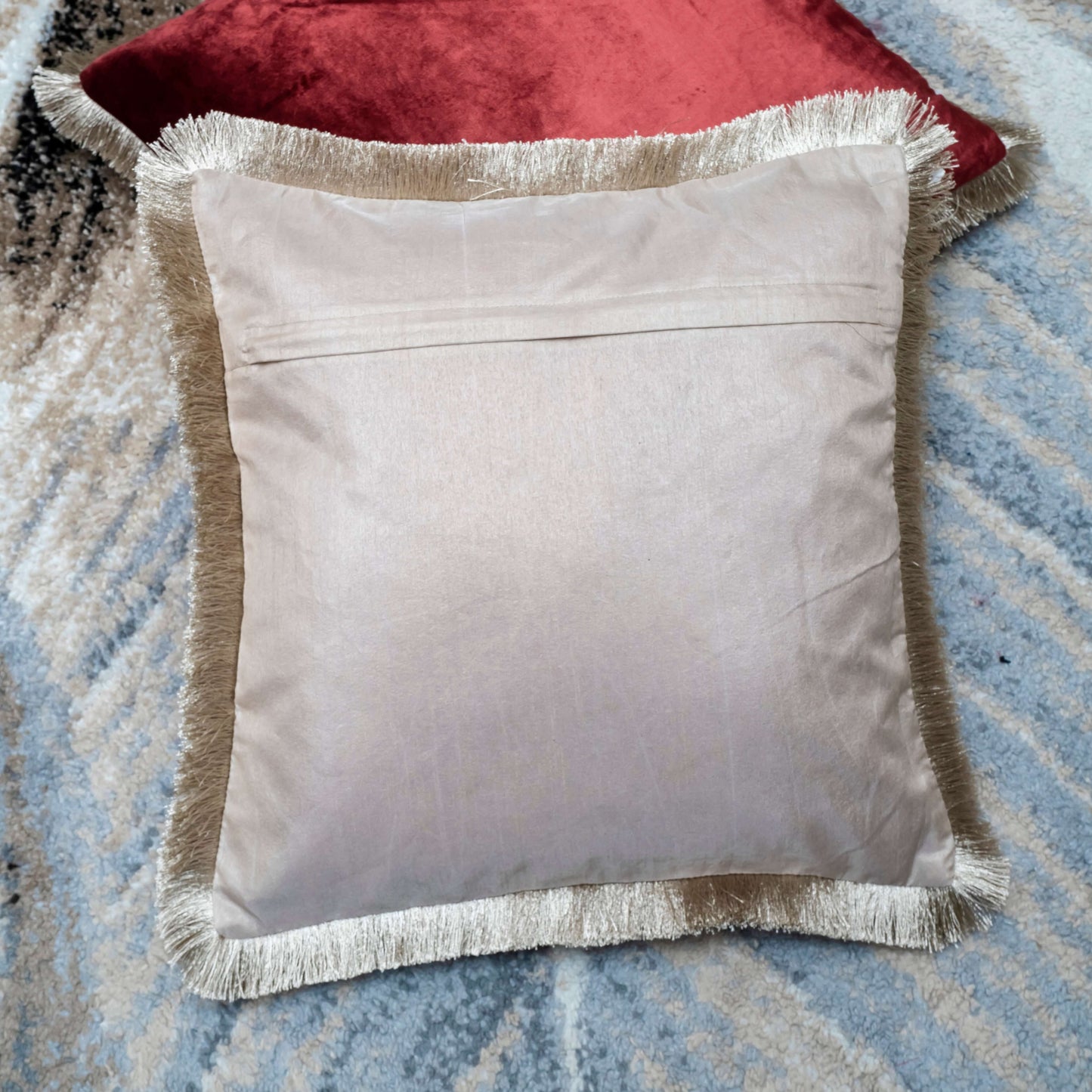 Gray pillow with fringe on a textured surface
