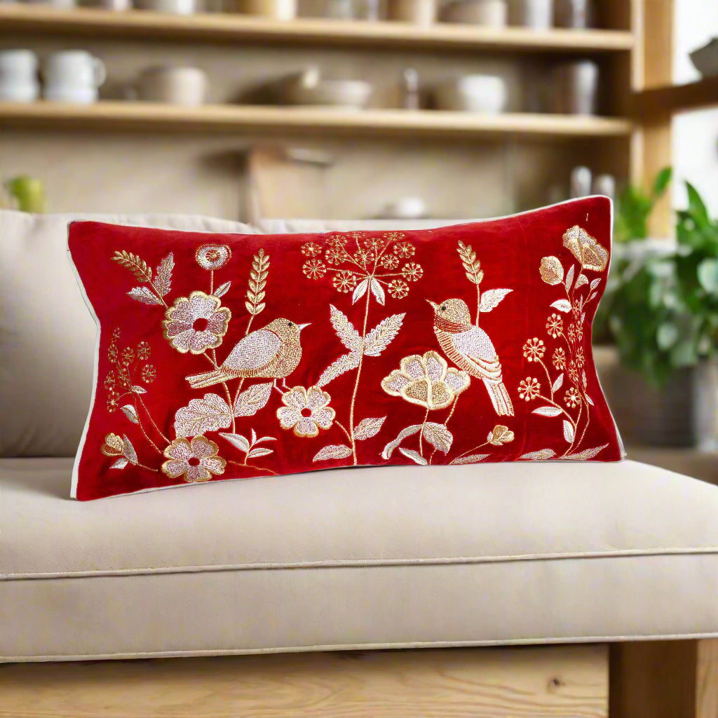 Red pillow with floral and bird pattern on a white background