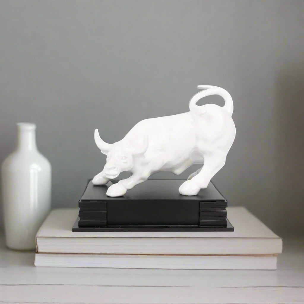 White bull sculpture on a black base against a white background