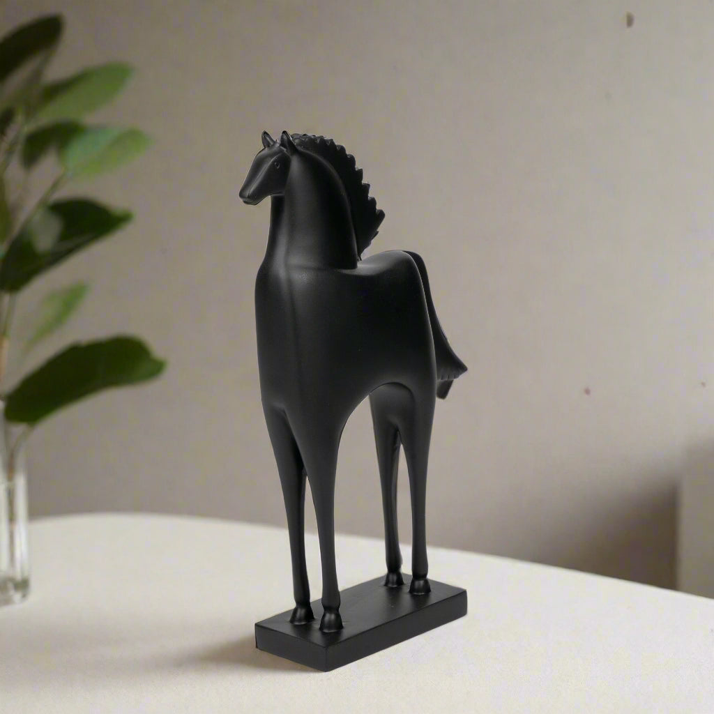 Black horse statue on a white surface with a neutral background