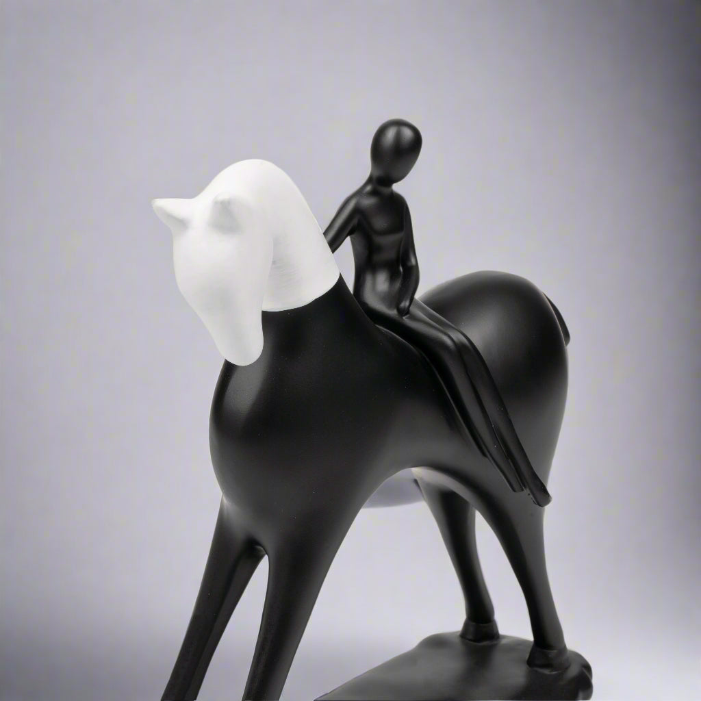 Black and white sculpture of a horse with a rider on a white background