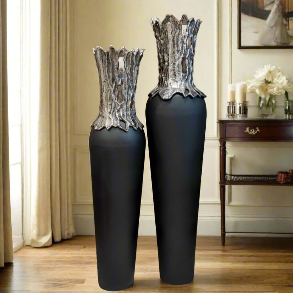 Two large black vases with decorative tops in a room setting.