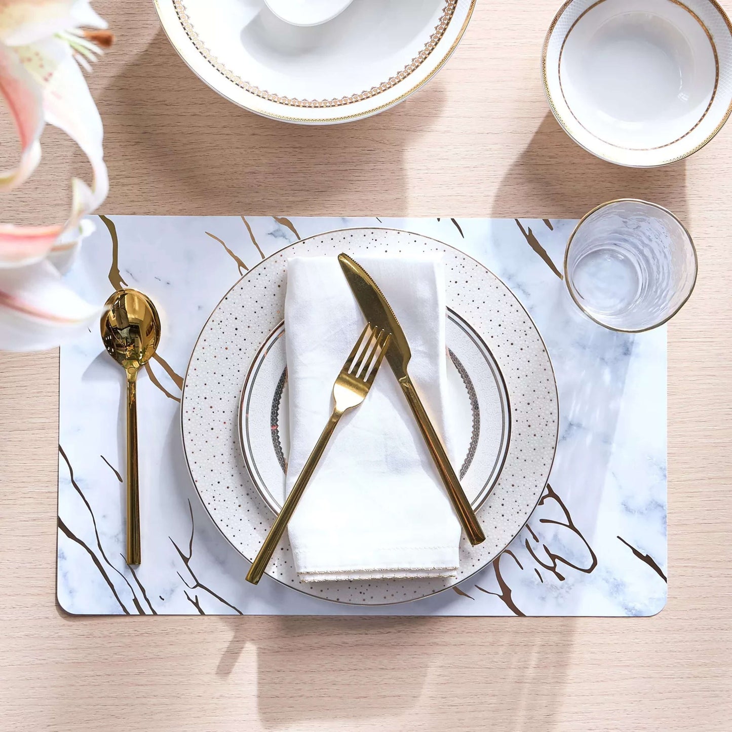 Table setting with gold cutlery on a marble placemat