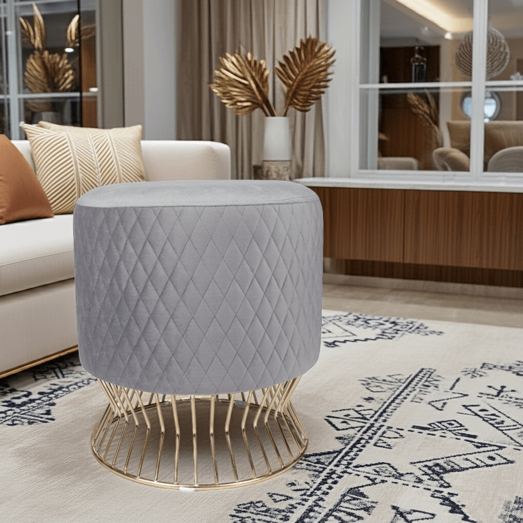 Elegant Gray Quilted Velvet Ottoman with Gold Base in a modern living room setting.