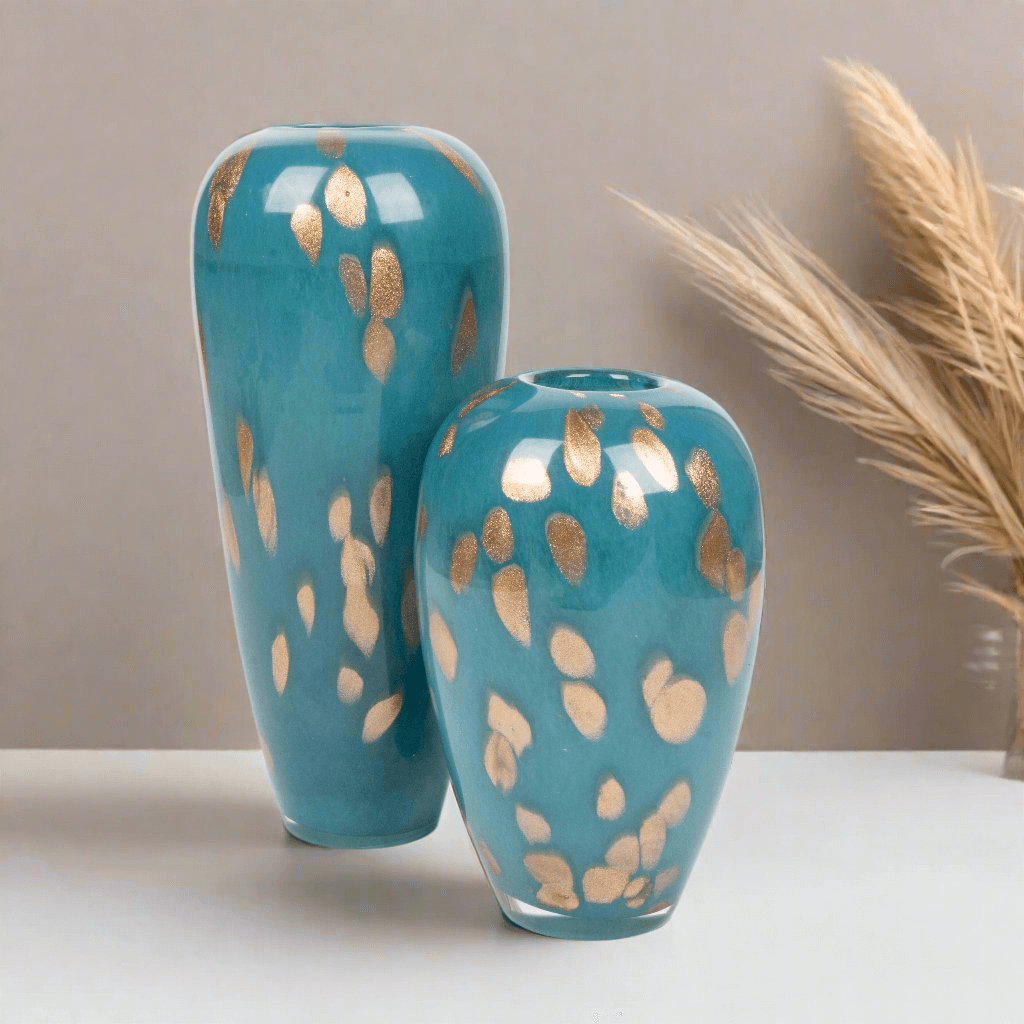 Two turquoise vases with gold leaf patterns on a neutral background